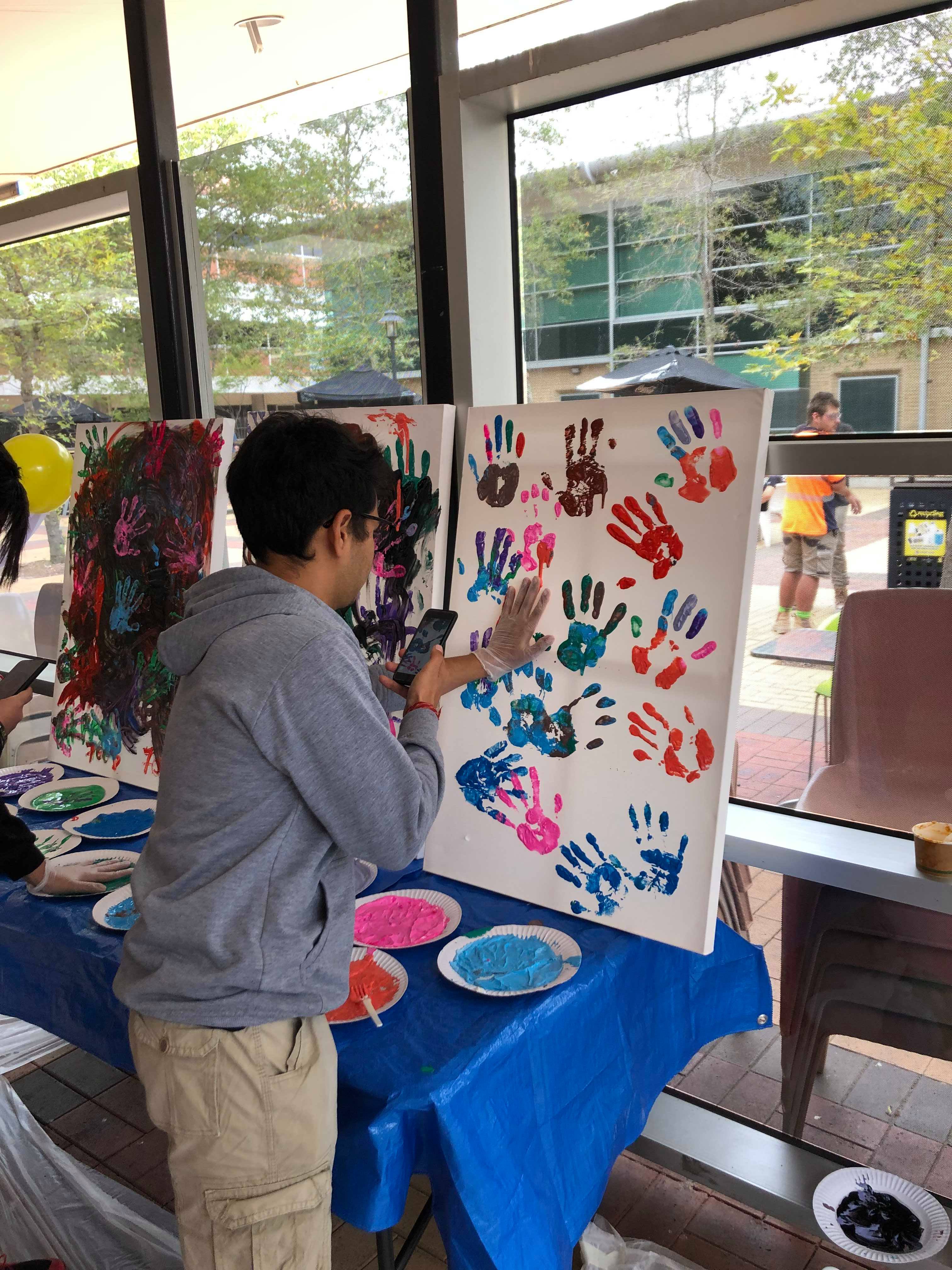 Student places his colourful hand print to celebrate Holi Festival